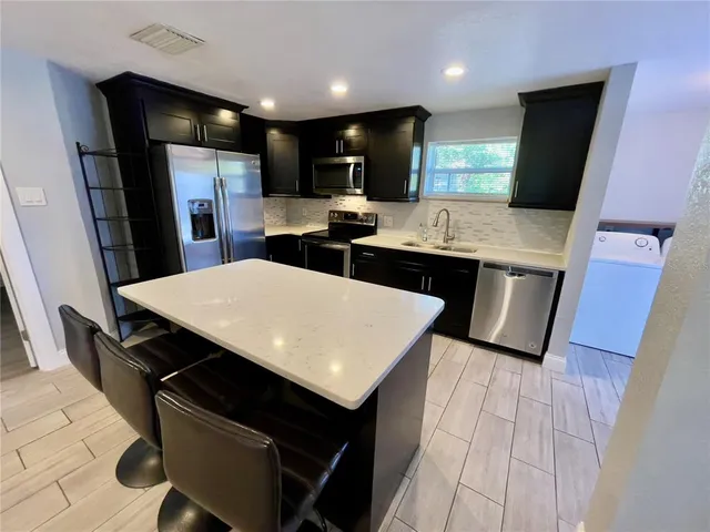 a kitchen with stainless steel appliances a sink a stove a refrigerator and cabinets