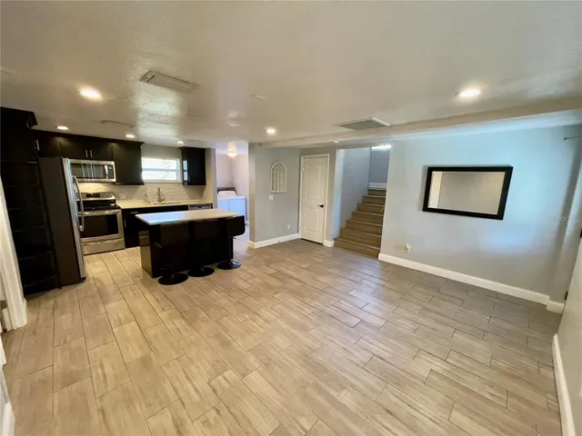 a large kitchen with stainless steel appliances kitchen island a large counter top and a wooden floors