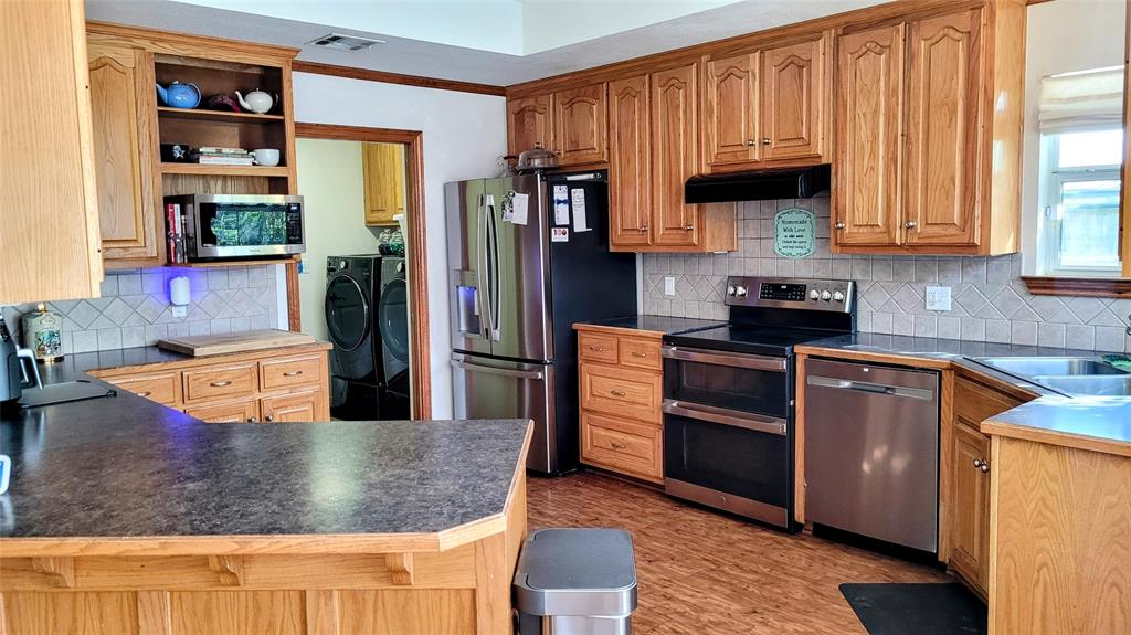 3164 Clater Powell Road Waco, TX 76705 - Photo 20 of 40 a kitchen with stainless steel appliances granite countertop a refrigerator a stove and a sink with wooden floor