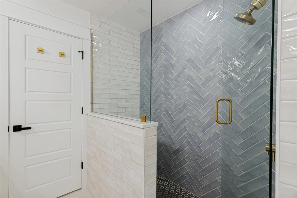 4316 Springbranch Drive Benbrook, TX 76116 - Photo 26 of 39 Shower enclosure with clear glass panels, herringbone-patterned blue-gray subway tile, and a brass-finish shower handle