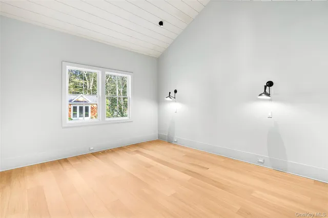 an empty room with wooden floor fireplace and windows