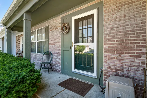a view of a door with a chairs and bench in the porch