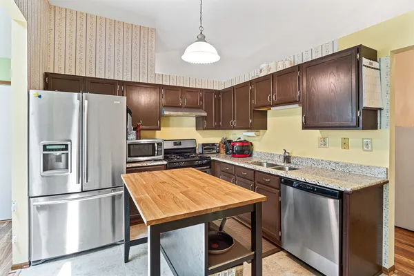 a kitchen with stainless steel appliances a refrigerator a sink a stove a table and chairs