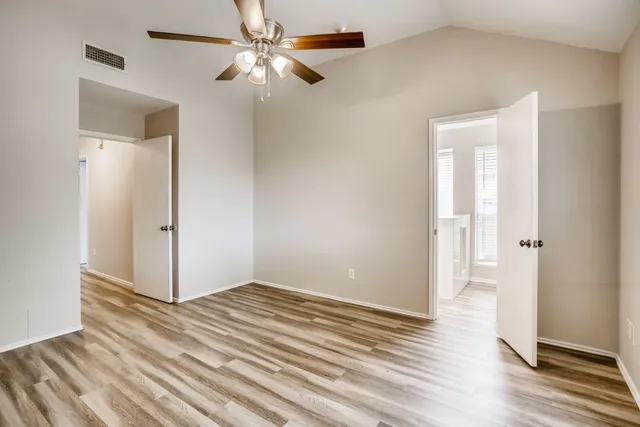 an empty room with wooden floor closet and windows
