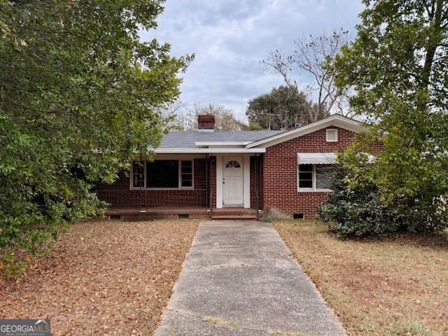 a front view of a house with a garden and trees