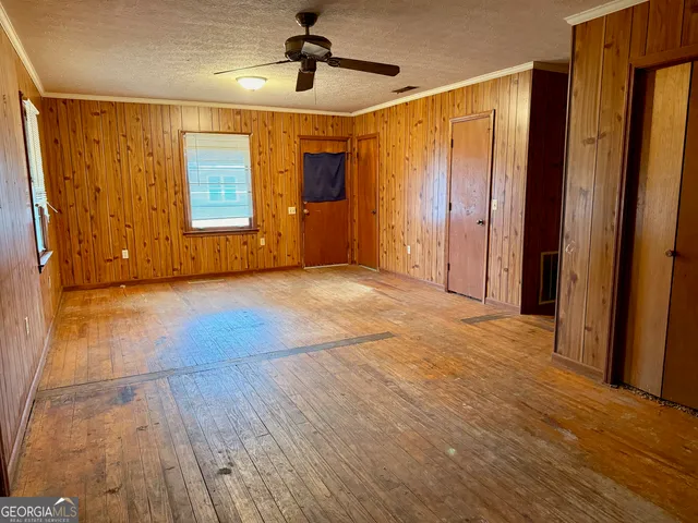 a view of empty room with wooden floor and fan