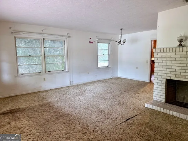 an empty room with windows and fireplace