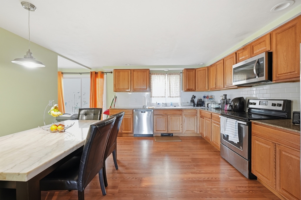 5 Swan Avenue, Unit B Worcester, MA 01602 - Photo 6 of 25 a kitchen with stainless steel appliances granite countertop a stove top oven a sink a dining table and chairs with wooden floor