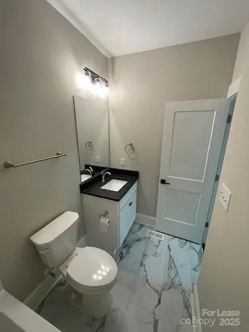 a bathroom with a granite countertop toilet sink and mirror