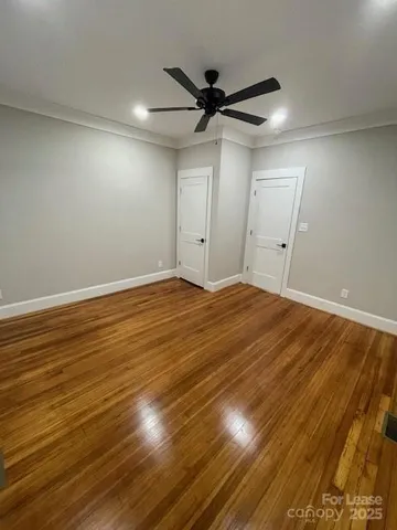 a view of a room with wooden floor and a ceiling fan