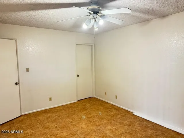 an empty room with a ceiling fan and carpet
