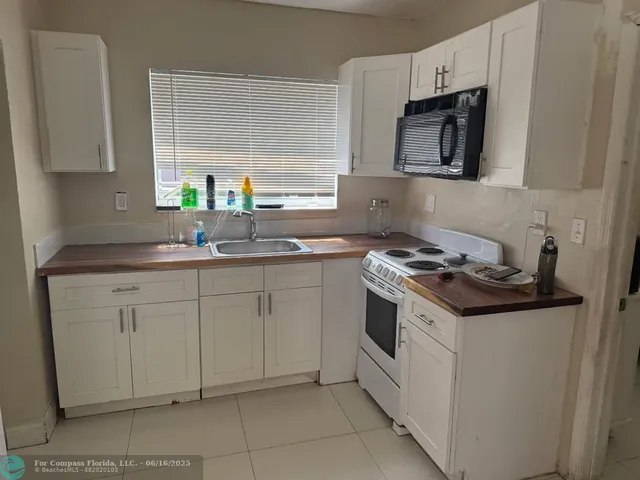 a kitchen with stainless steel appliances granite countertop white cabinets a sink a stove a microwave a counter space and cabinets