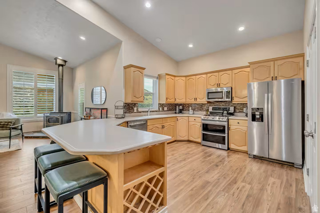 11789 Nicklaus Road Sandy, UT 84092 - Photo 9 of 58 Kitchen with stainless steel appliances, a peninsula, light wood finish cabinetry, lofted ceiling, and light countertops