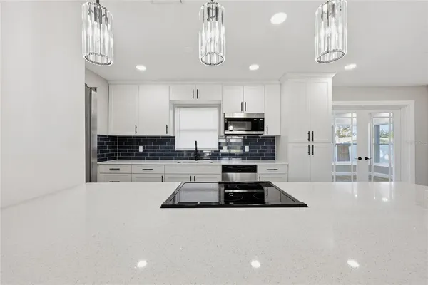 a large white kitchen with kitchen island a sink stainless steel appliances and cabinets