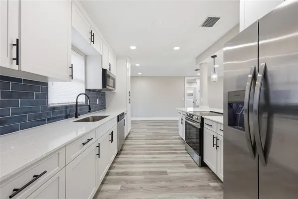 a large kitchen with stainless steel appliances lots of counter space and a sink
