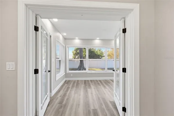 a view of a hallway with wooden floor and a bathroom