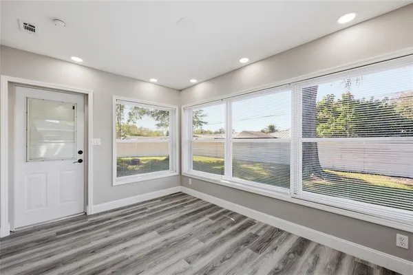 a view of an empty room with wooden floor and a window