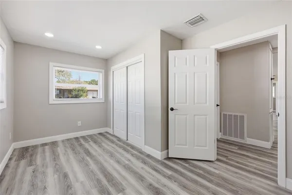 a view of hallway with window and wooden floor