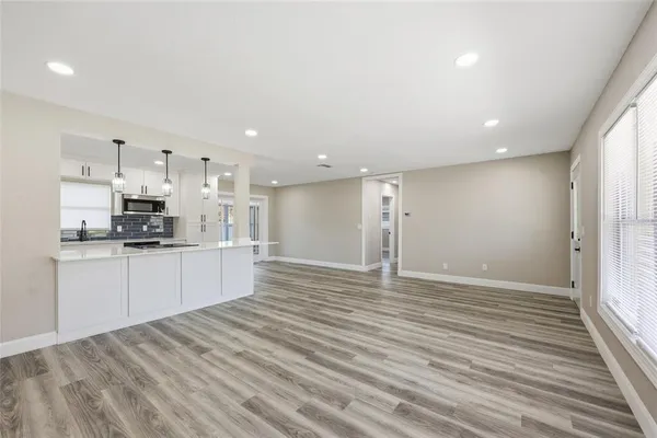 a large white kitchen with kitchen island a sink stainless steel appliances and cabinets