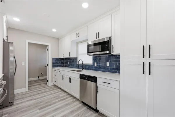 a kitchen with white cabinets stainless steel appliances and a refrigerator