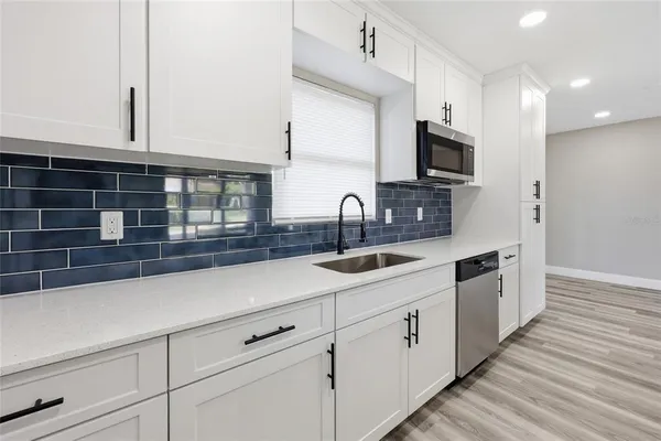 a kitchen with white cabinets and sink