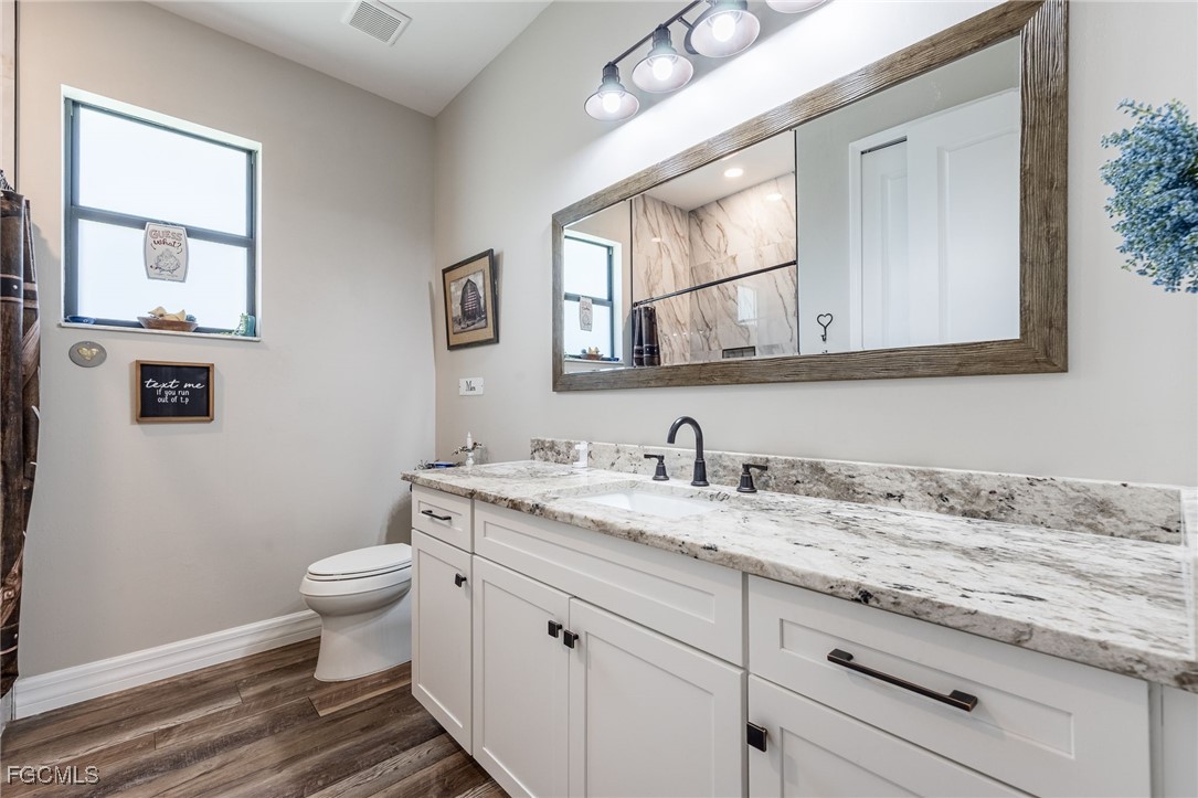 2391 Lippincott Road Alva, FL 33920 - Photo 31 of 50 a bathroom with a granite countertop toilet sink and mirror