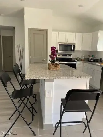 a kitchen with stainless steel appliances kitchen island granite countertop a stove a sink a microwave and a refrigerator