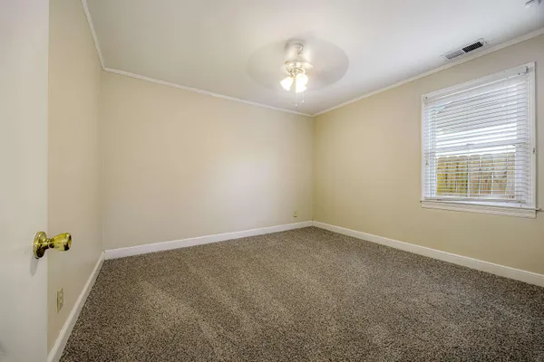 an empty room with a chandelier fan and windows