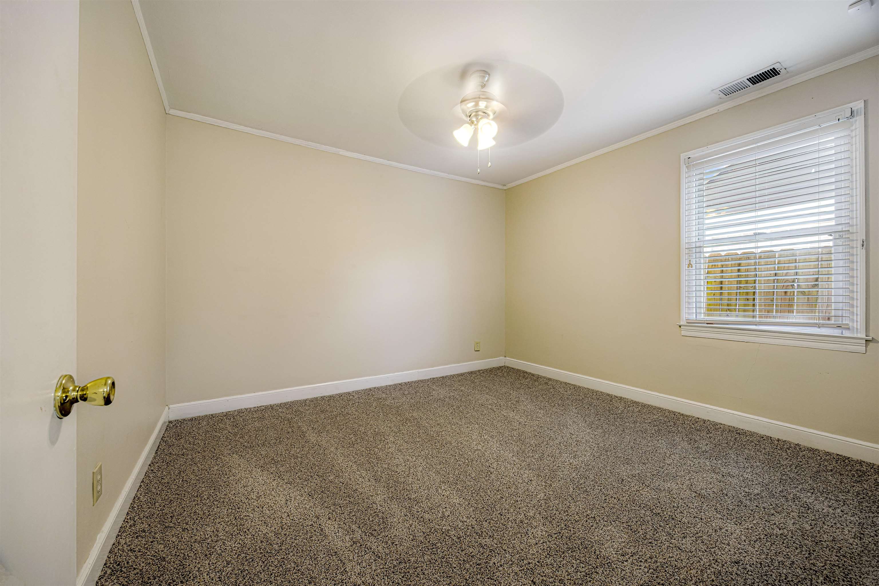 an empty room with a chandelier fan and windows