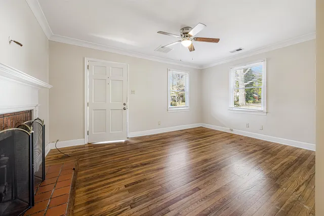 a view of an empty room with wooden floor and a window