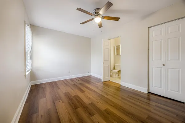 an empty room with wooden floor and ceiling fan