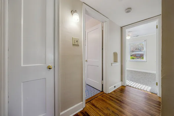 a view of a hallway with wooden floor and a bathroom