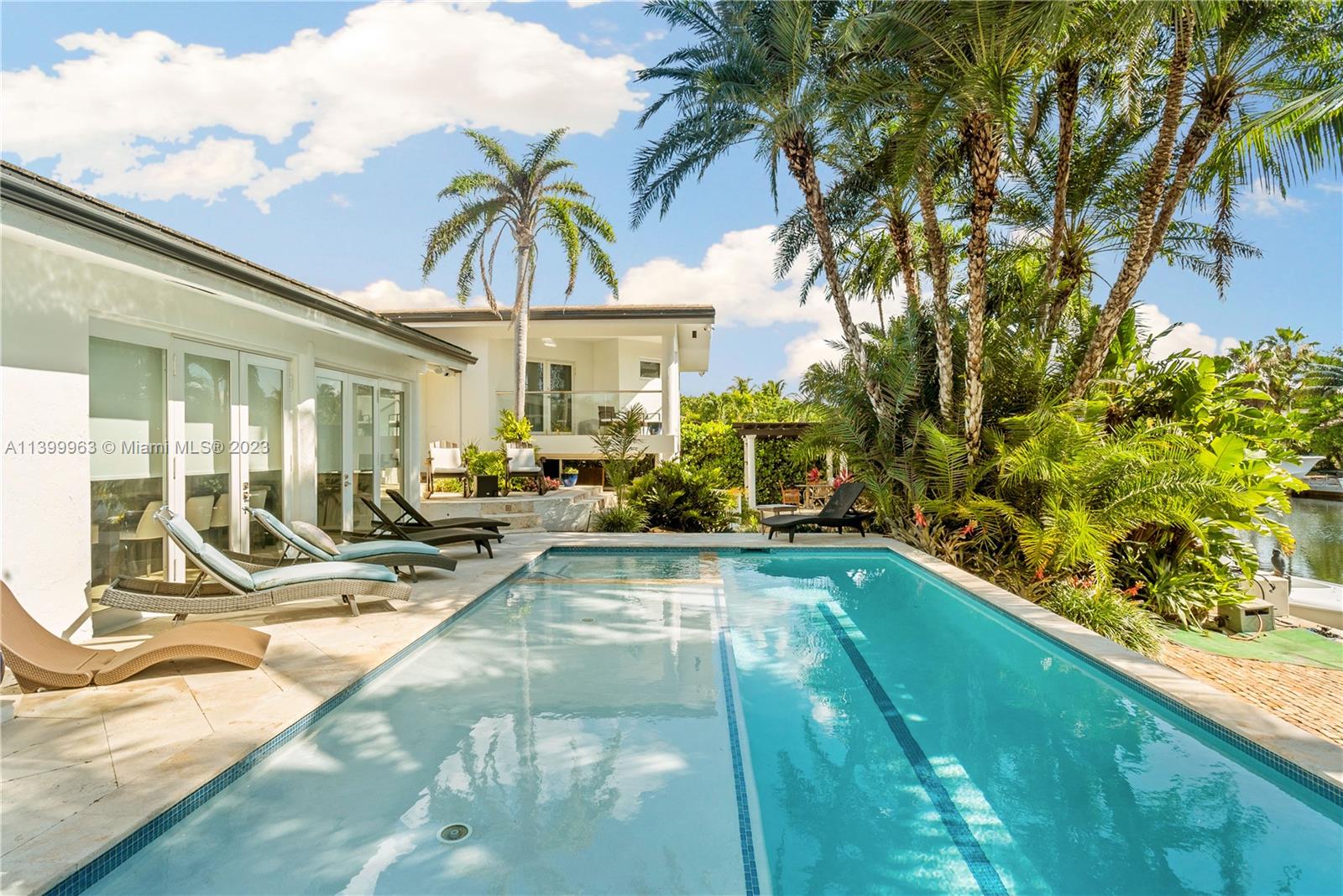 12521 Ramiro Street Coral Gables, FL 33156 - Photo 35 of 53 a view of a swimming pool with a lounge chair and palm trees