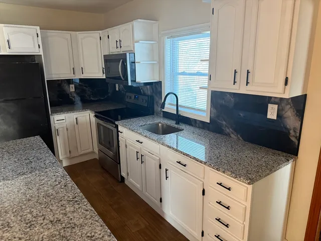 a kitchen with granite countertop white cabinets and stainless steel appliances