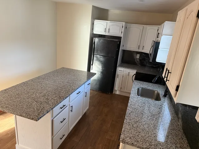 a kitchen with granite countertop a refrigerator a stove a microwave a sink and dishwasher