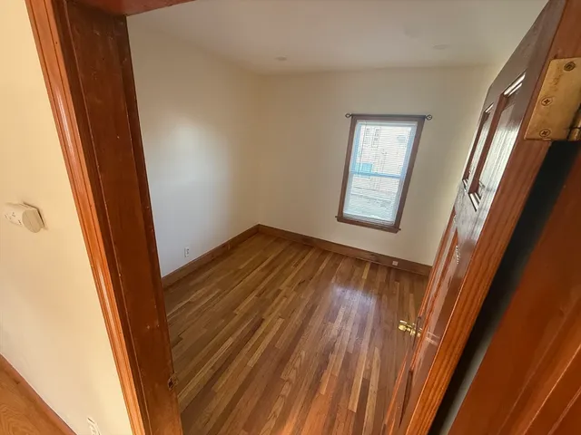 a view of empty room with window and wooden floor