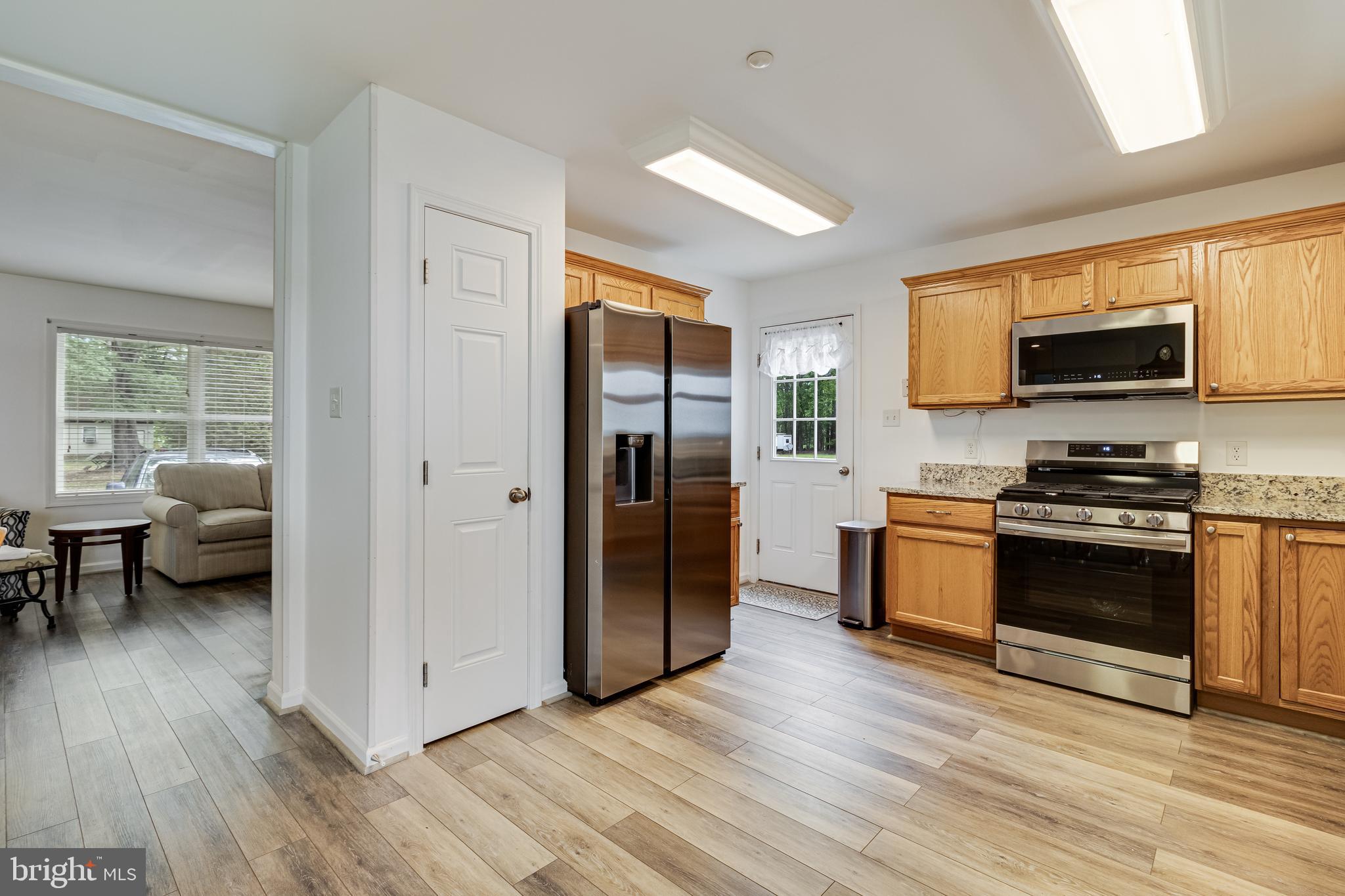 12015 Woodbury Road Nanjemoy, MD 20662 - Photo 22 of 53 a kitchen with stainless steel appliances a stove a refrigerator a sink a stove and a wooden floors