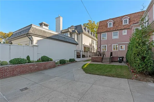 a view of a brick house with a yard plants and large tree