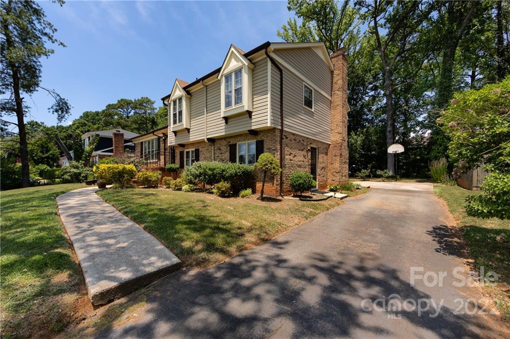 7433 Riding Trail Road Charlotte, NC 28212 - Photo 3 of 42 a view of a white house with a yard plants and large trees