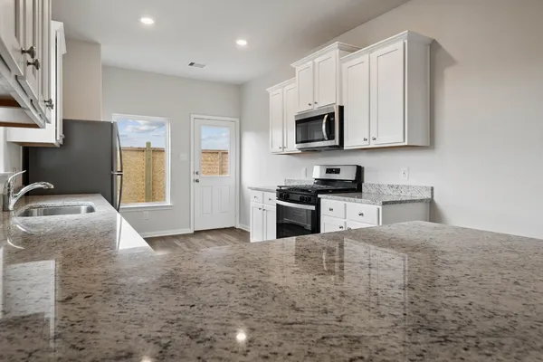 a kitchen with granite countertop a sink a stove and cabinets