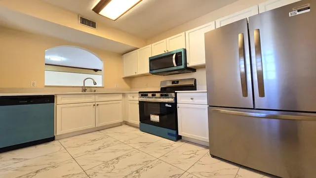 a kitchen with stainless steel appliances granite countertop a refrigerator sink and stove