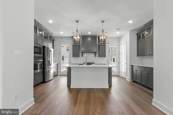 a large kitchen with a center island wooden floor stainless steel appliances and a window