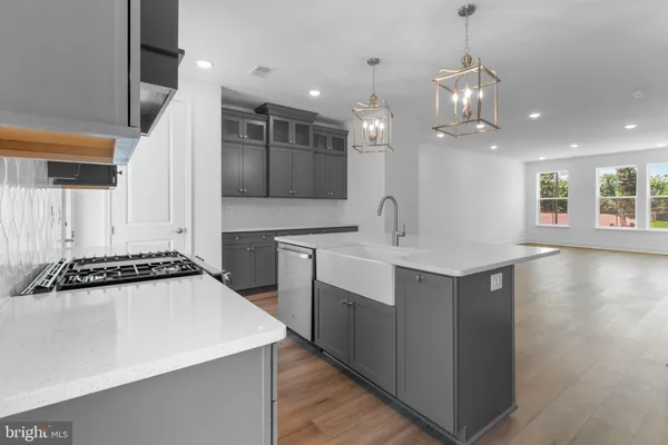 a large white kitchen with a large counter top a sink stainless steel appliances and cabinets