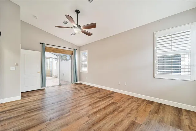 a view of empty room with wooden floor and fan