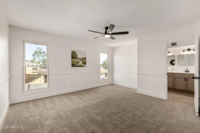 a view of a livingroom with a ceiling fan & windows