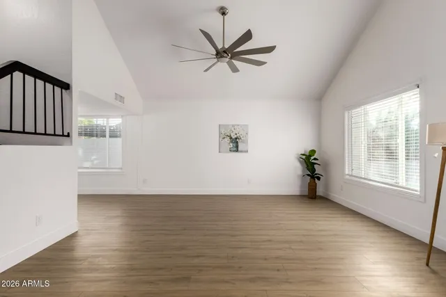 a view of an empty room with a window and wooden floor
