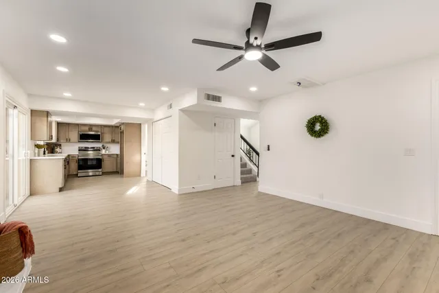 a view of an empty room with kitchen appliances and a ceiling fan