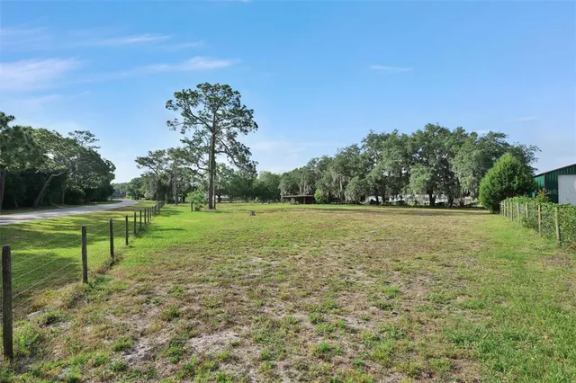 a view of a green field with wooden fence