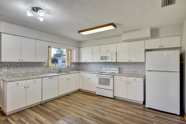 a kitchen with granite countertop white cabinets and white appliances
