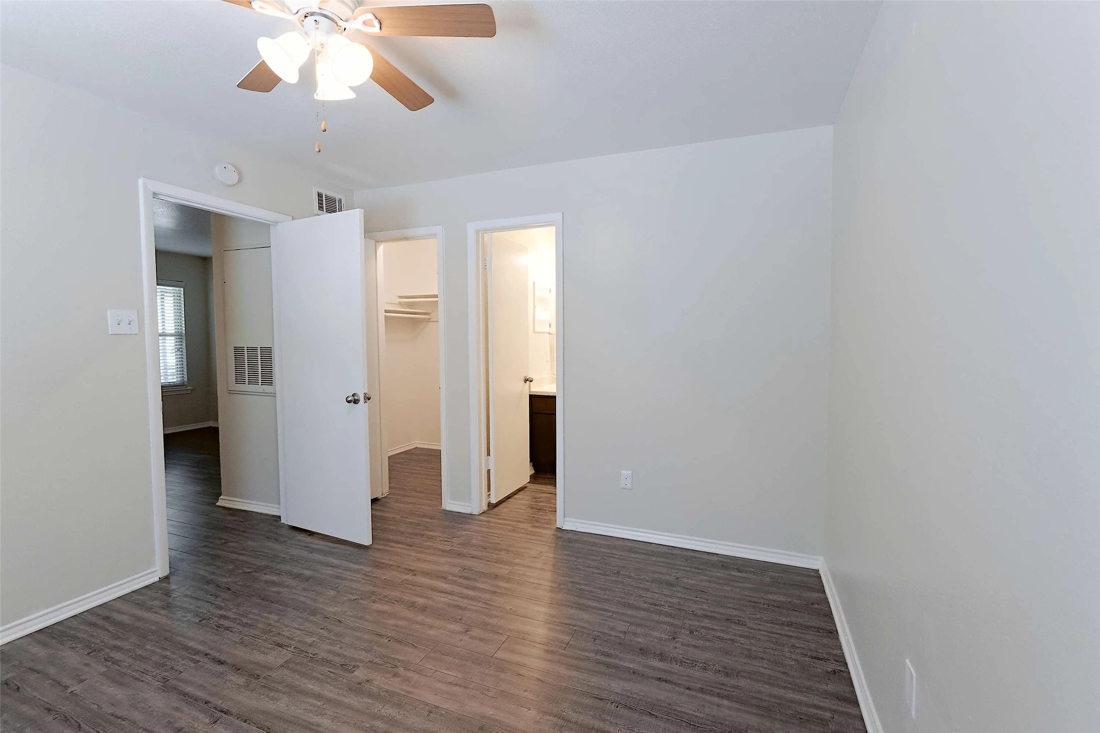 2809 West William Cannon Drive, Unit I101 Austin, TX 78745 - Photo 8 of 29 Unfurnished bedroom featuring dark wood-type flooring, a spacious closet, and a ceiling fan